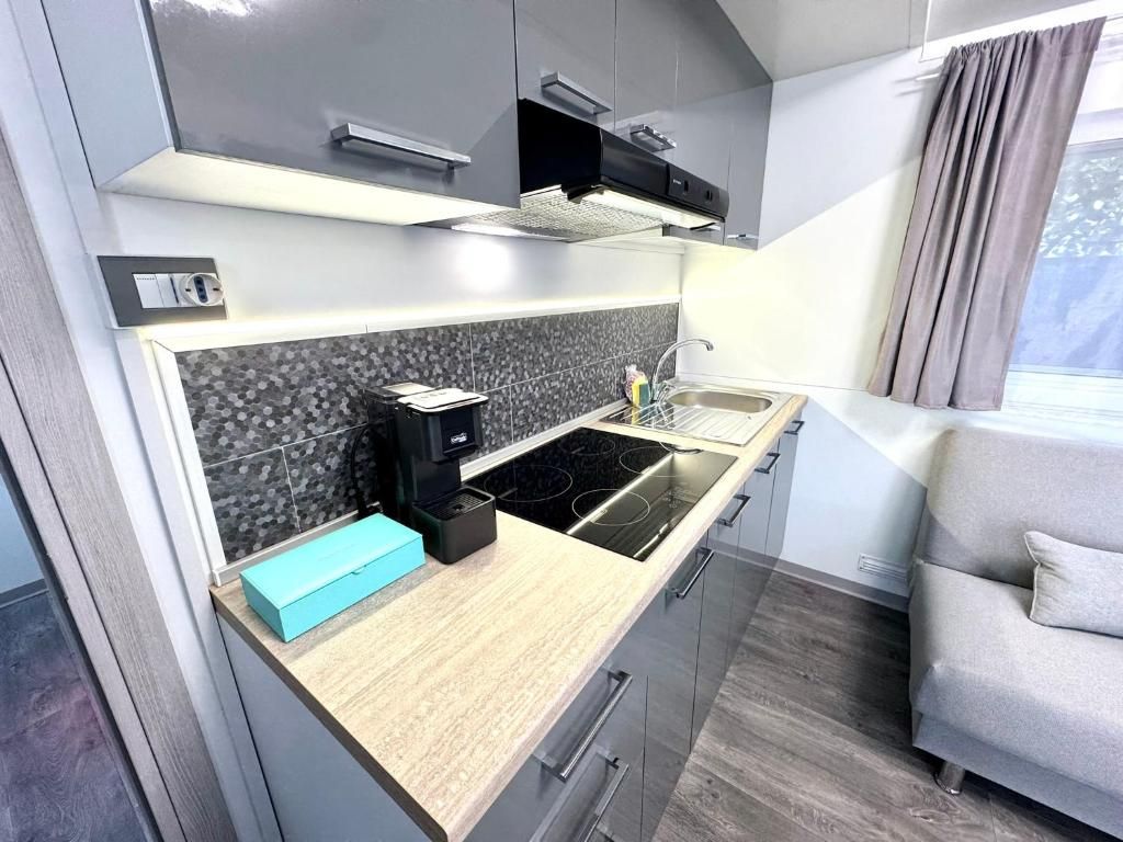 A modern kitchen with a built-in stove, a sink, and a window with curtains.