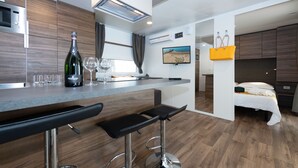 A modern kitchen with a bar area, a bed, and a TV. - Luxury Camp at Union Lido (Cavallino-Treporti)