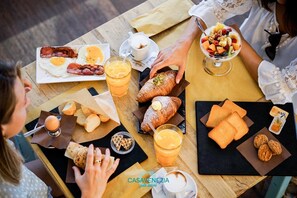 Ein Frühstückstisch mit Croissants, Gebäck und einer Obstschale.