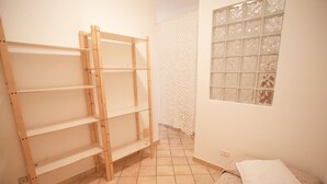 Una habitación con un armario de madera, una cama con colcha estampada y una ventana con cortina decorada.