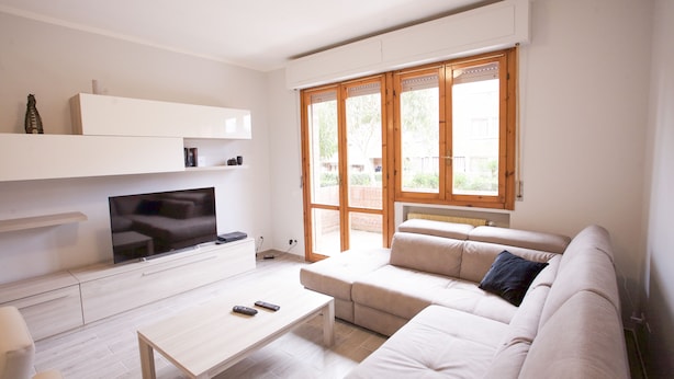 A modern living room with a flat-screen TV, a sofa, a coffee table, and a sliding glass door leading to an outdoor area. - Appartamento il Quadrifoglio (Portoferraio)