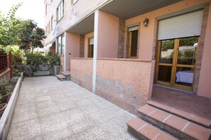 A residential building with a balcony, a small garden, and a door with a window.