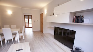 A modern living room with a flat-screen TV, a coffee table, and a dining area with chairs. - Appartamento il Quadrifoglio (Portoferraio)
