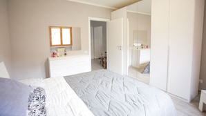 A bedroom with a bed, a dresser, a mirror, and a wardrobe. - Appartamento il Quadrifoglio (Portoferraio)