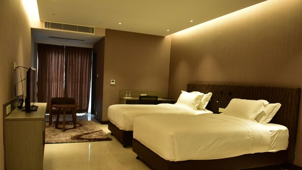 A hotel room with two beds, a desk, and a chair. - Divine Center (Chowgacha)