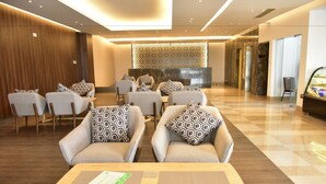 A modern lobby with sofas and chairs, a reception desk, and a decorative wall. - Divine Center (Chowgacha)