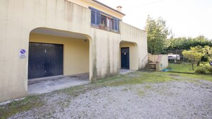 A building with two large doors, a small balcony, and a gravel driveway. - Villino Mediterraneo (Portoferraio)