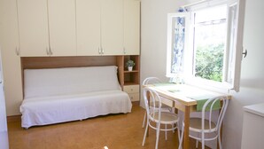 A bedroom with a bed, a desk, two chairs, a window with curtains, and a wardrobe. - Appartamento il Mandarino (Portoferraio)