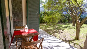 An outdoor patio with a wooden table and chairs, a red tablecloth, and a lantern. - Appartamento il Mandarino (Portoferraio)