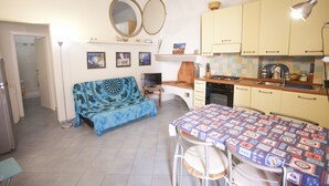 A compact kitchen with a dining area, a sofa, and a TV.