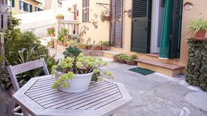 A wooden table with potted plants in a courtyard with buildings in the background.