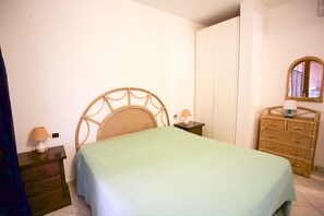 Een slaapkamer met een bed, nachtkastje, dressoir en spiegel.