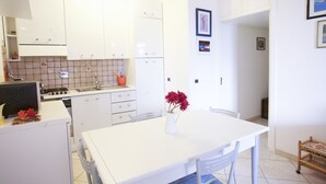 A modern kitchen with white cabinets, a white countertop, and a dining table with chairs.