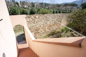 A stone retaining wall with a staircase leading to a covered area.