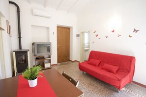 A living room with a red sofa, a wooden table, a TV, and a plant.