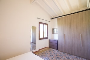 Una camera da letto con un letto, un armadio, una cassettiera, una finestra e pavimento decorato.