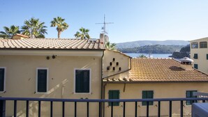 A coastal building with a tiled roof, green shutters, and a visible antenna.