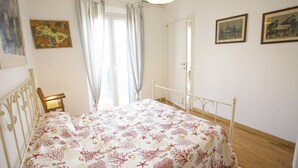 A bedroom with a bed, a nightstand, a window with curtains, and two wall-mounted paintings.