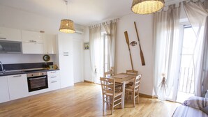 A modern kitchen with white cabinets, a wooden dining table with chairs, and a wooden floor.