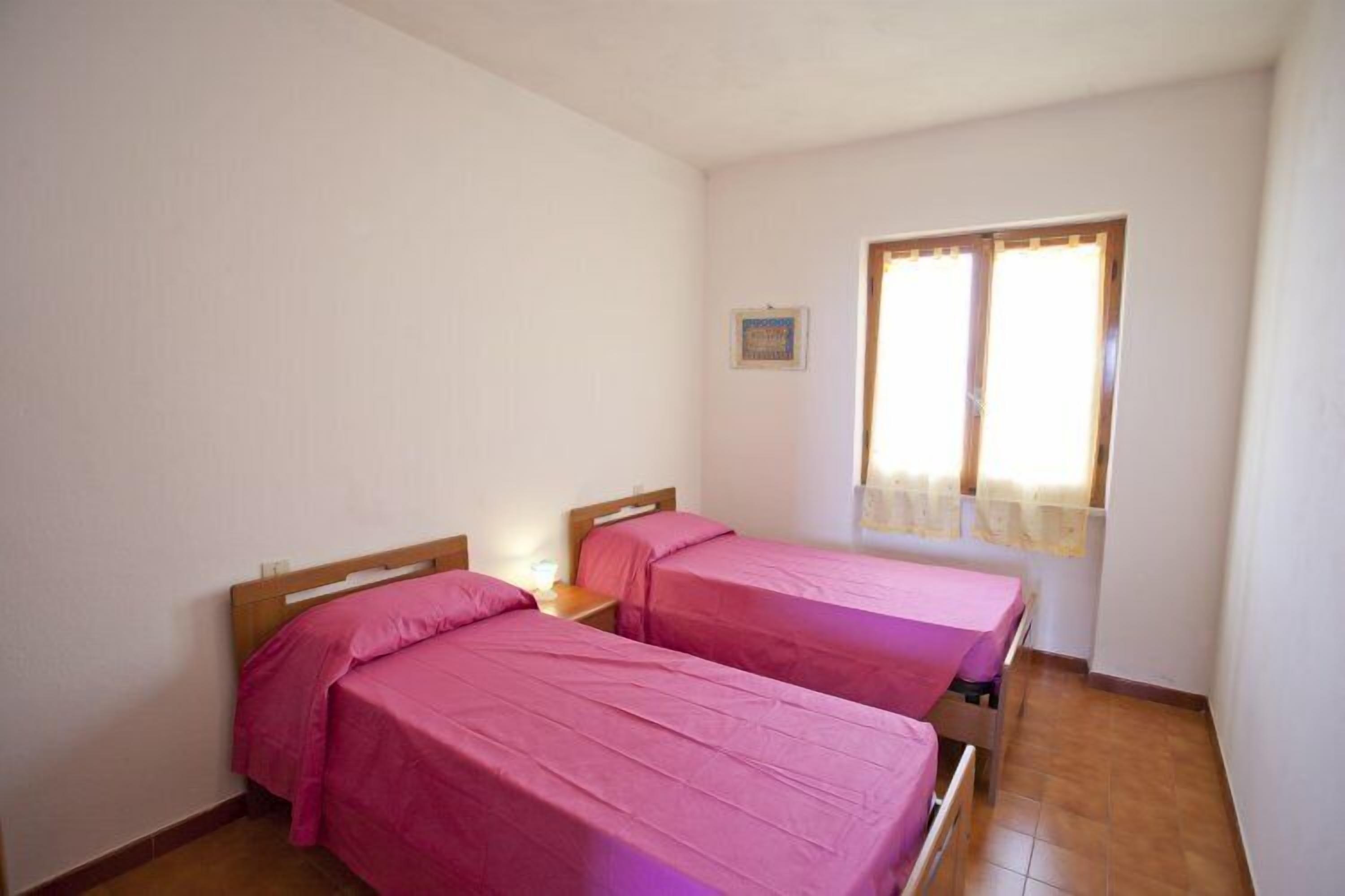 Une chambre avec deux lits, une fenêtre avec des rideaux et un petit tableau accroché au mur.