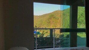 Habitación de hotel con cama, una mesita y ventana con vistas a un paisaje verde.