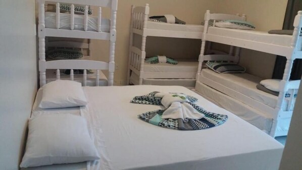 Una habitación con literas, una cama individual con almohada y una manta en el suelo.