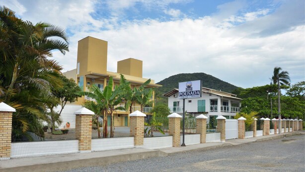 Un edificio de dos pisos con un letrero que dice "POUSADA" y una montaña al fondo.