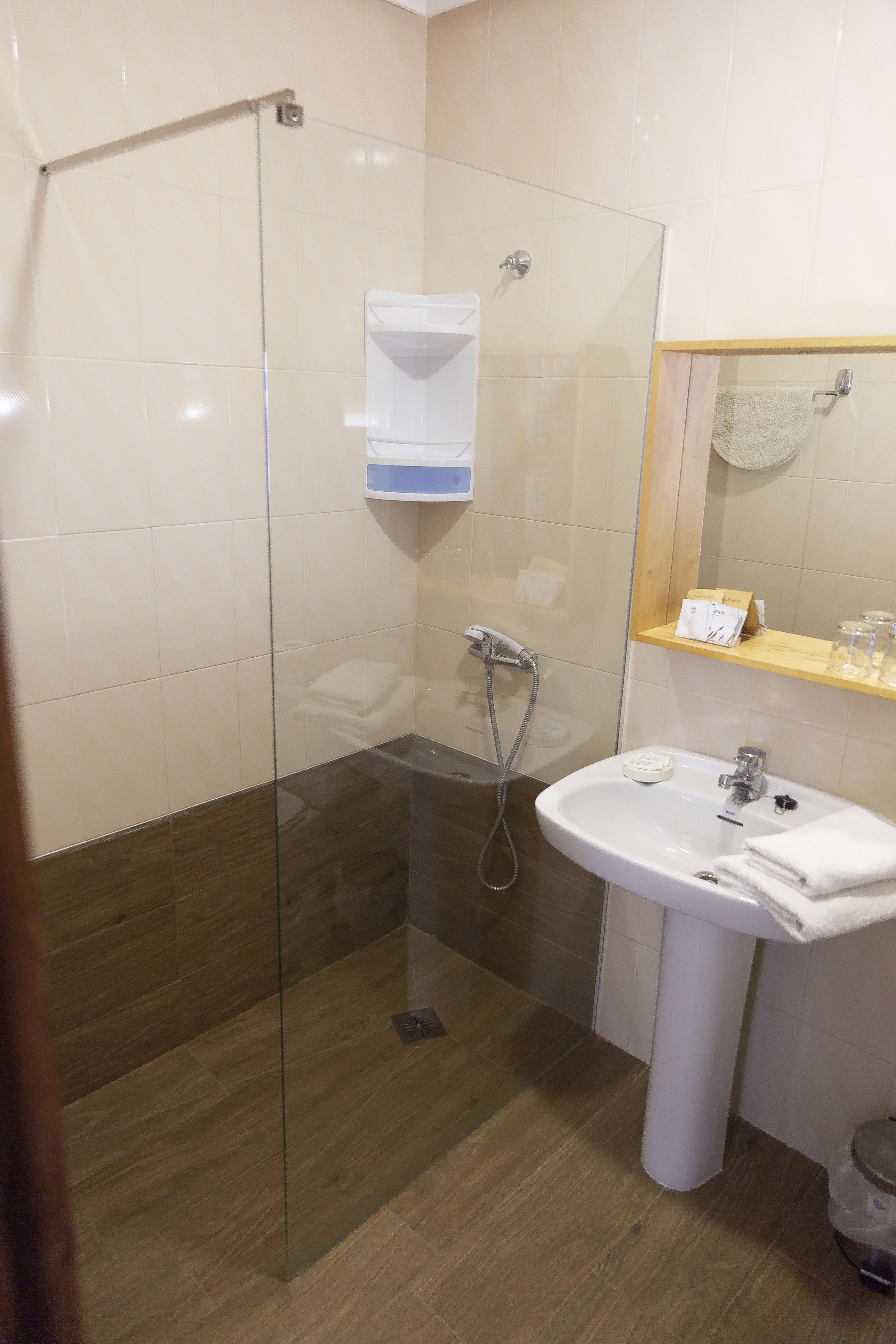 Un baño con cabina de ducha de vidrio, un lavabo blanco y un espejo sobre él.