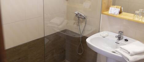 Une salle de bain avec une douche à parois de verre, un lavabo blanc et un miroir au-dessus du lavabo.