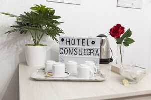 Um letreiro de hotel, uma planta em vaso, uma rosa e uma bandeja com xícaras de chá sobre uma mesa.