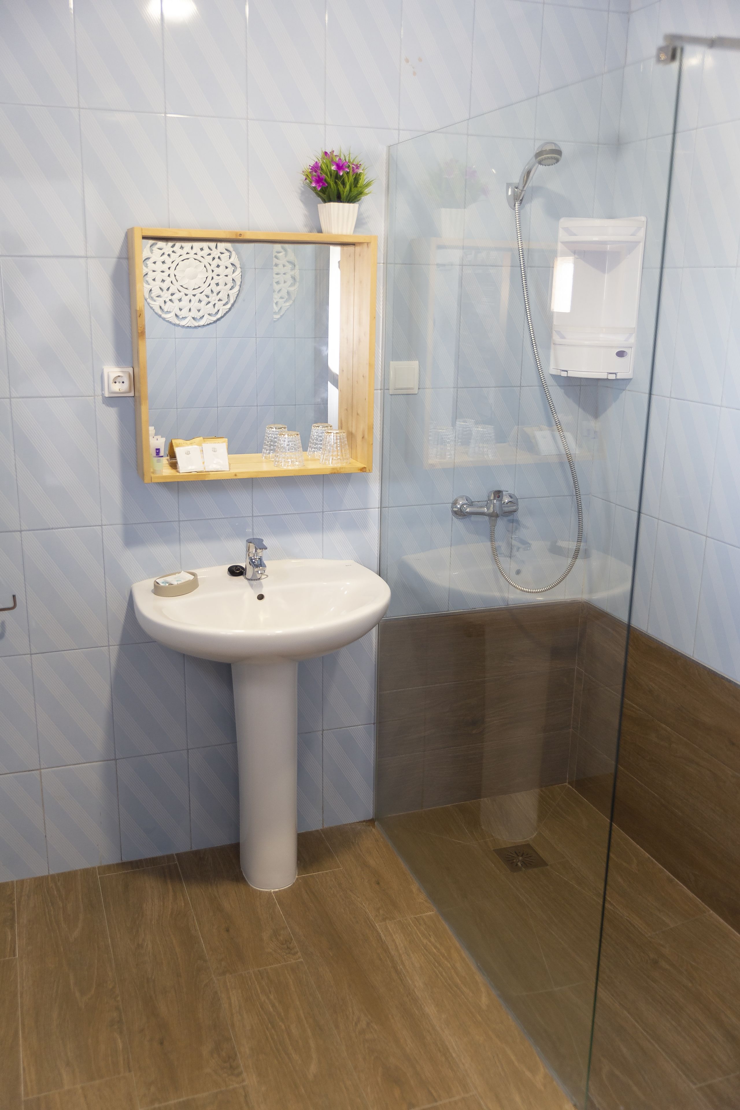 A bathroom with a pedestal sink, a glass shower enclosure, and a mirror with a decorative frame.