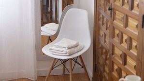 Un baño con una silla blanca, suelo de madera y un mueble de madera con cajones.