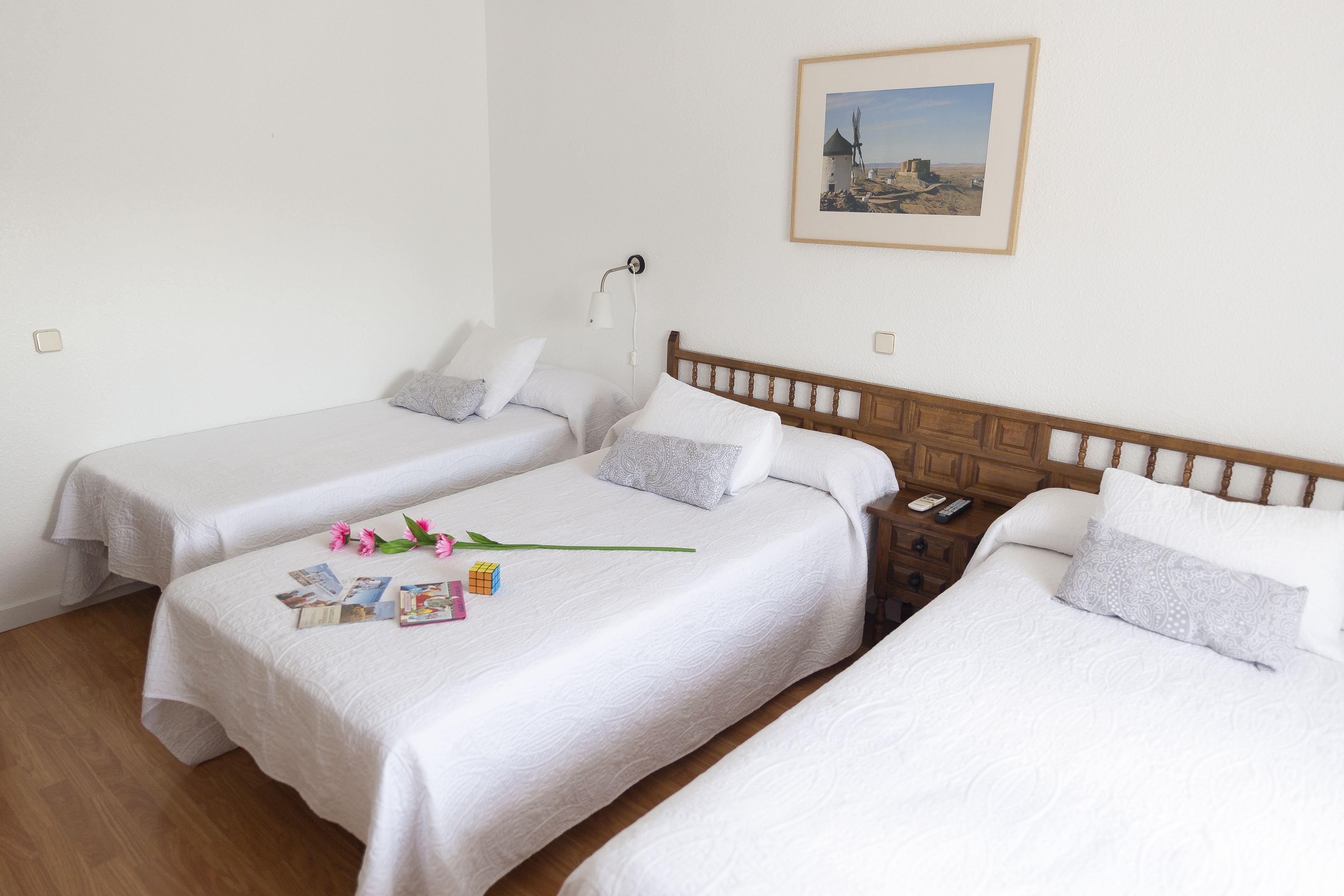 Una habitación de hotel con dos camas individuales, un cabecero de madera, una mesita de noche y una lámpara de pared.