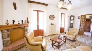 Ein Wohnzimmer mit Kamin, zwei Sesseln, einem Couchtisch und einer Wanduhr.