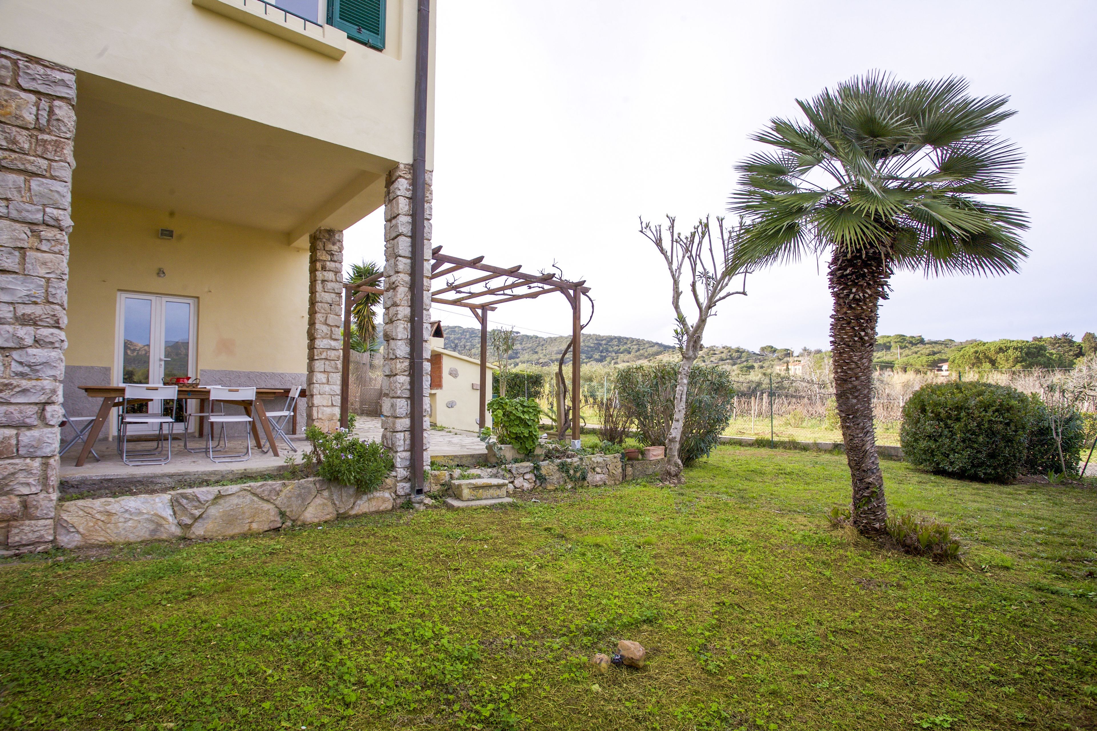 A stone building with a covered patio, outdoor seating, and a palm tree.