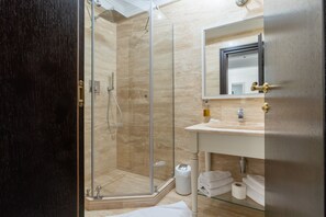 Een moderne badkamer met een douchecabine van glas, een witte wastafel en een grote spiegel.