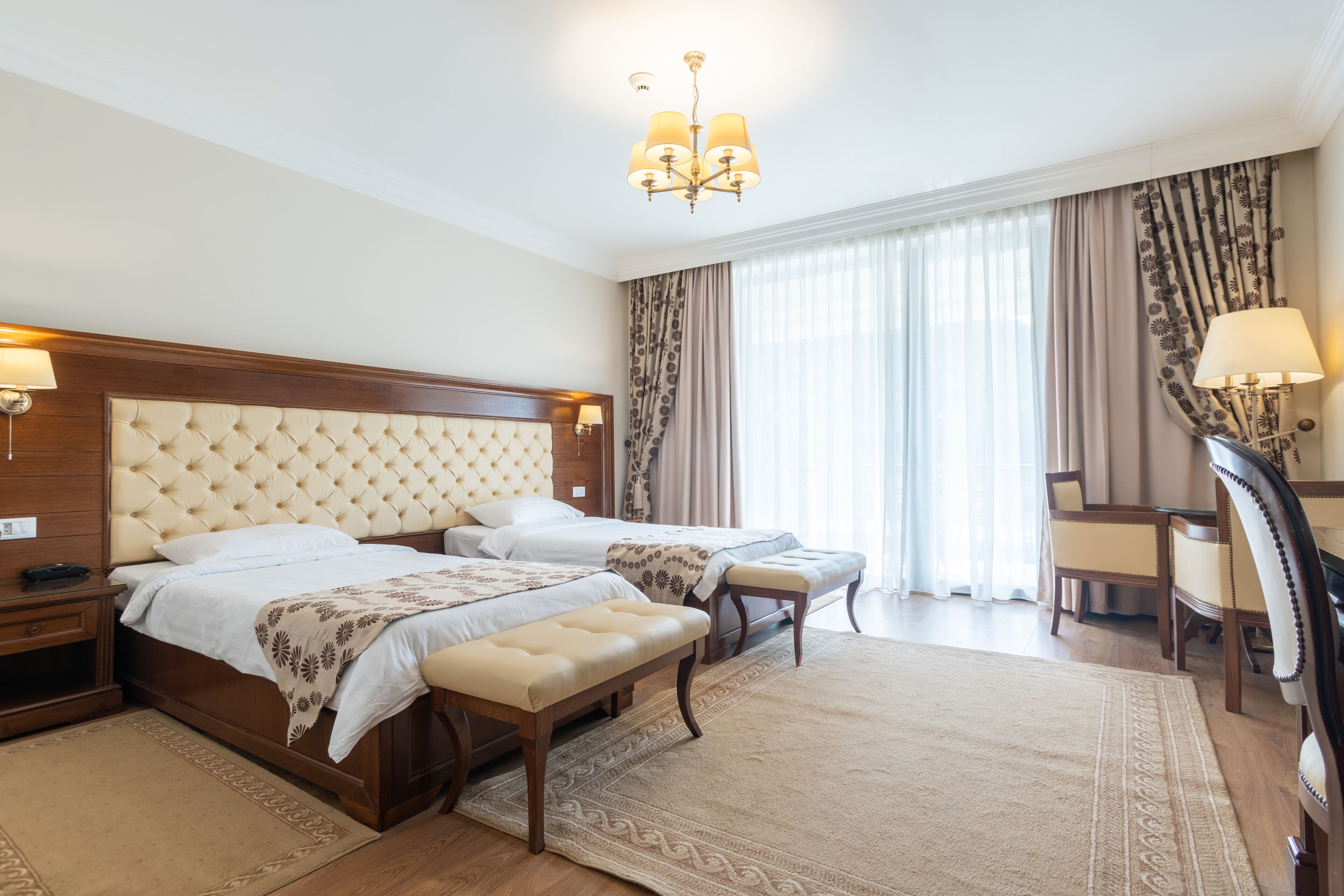 A hotel room with a large bed, two bedside tables, a desk, and a chair.