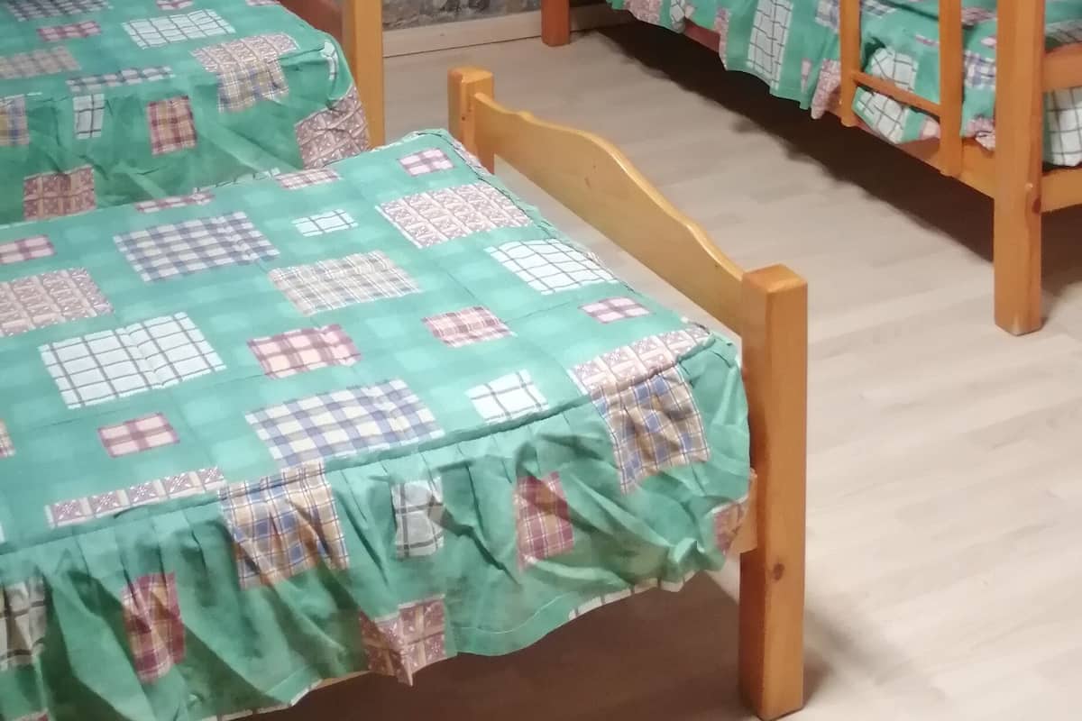 A dormitory room with bunk beds, a stone wall, and a ceiling fan.