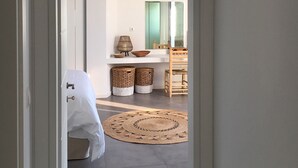 Un dormitorio con cama, una mesita de noche, un espejo y una alfombra redonda de fibras naturales.