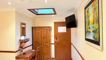 Una habitación de hotel con una cama, un escritorio, una silla, un televisor, un cuadro y una puerta.