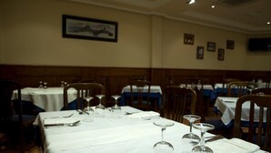 A restaurant with tables set for dining, featuring white tablecloths and wine glasses. - Hostal Restaurante San Poul (Consuegra)