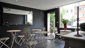 A modern interior with metal tables and chairs, a large mirror, and a view of the street outside. - Expo 13 (Ghent)