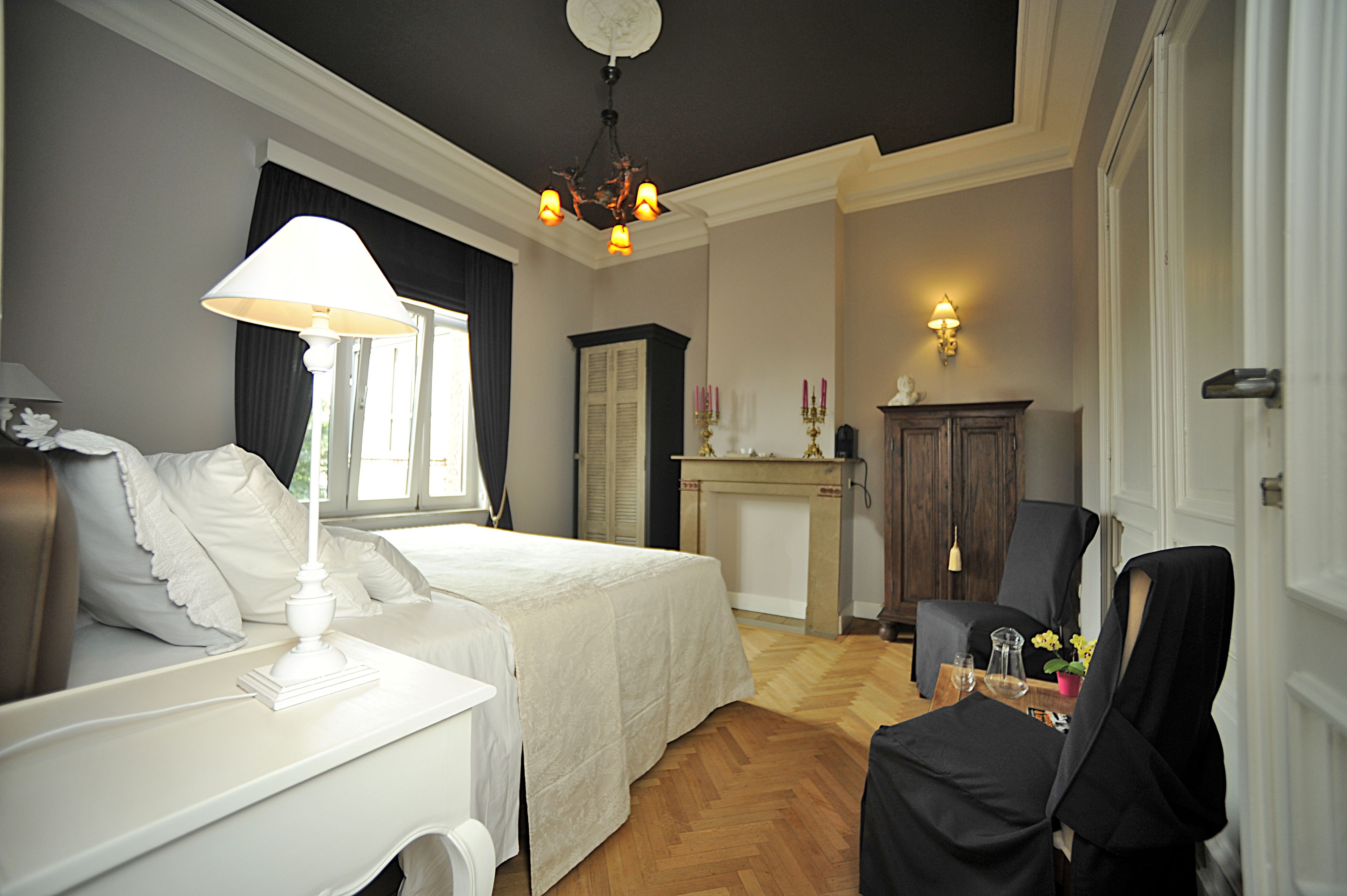 Een hotelkamer met een bed, nachtkastje, lamp en stoel.