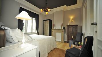 Een hotelkamer met een bed, nachtkastje, lamp en stoel.