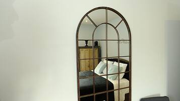 A room with a bed, a small table with a tray of breakfast items, and a mirror on the wall.