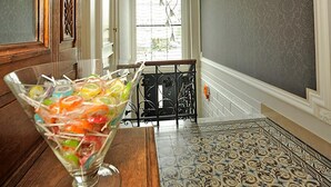 A hallway with a patterned floor, a glass bowl with colorful items, and a chandelier. - Expo 13 (Ghent)