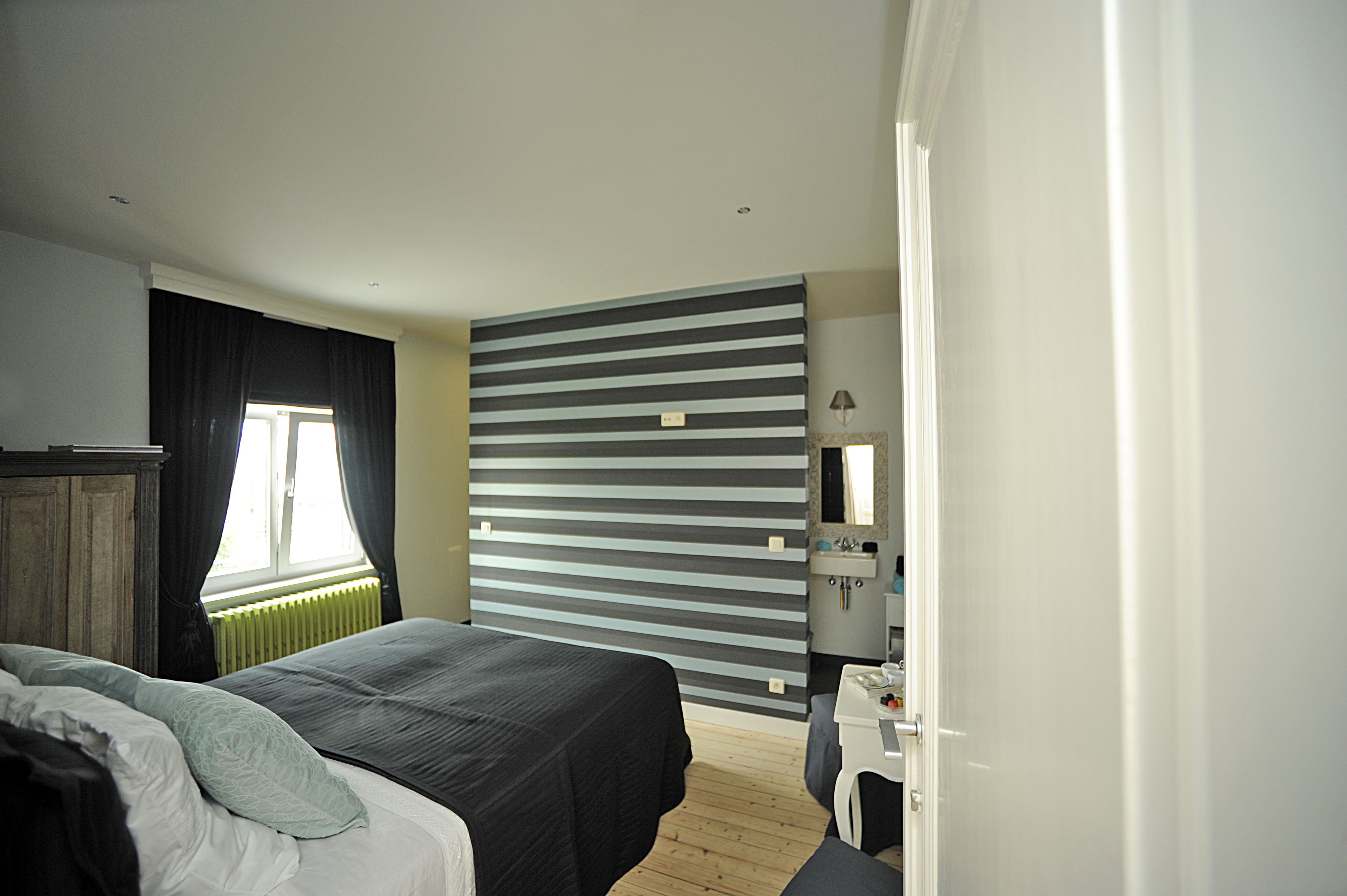 A modern hotel room with a large bed, a desk, and a radiator.