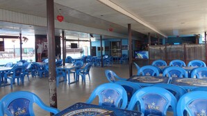 A restaurant with blue plastic chairs and tables, a wooden ceiling, and a view of the street outside. - DC Bar & Suites (Lagos)