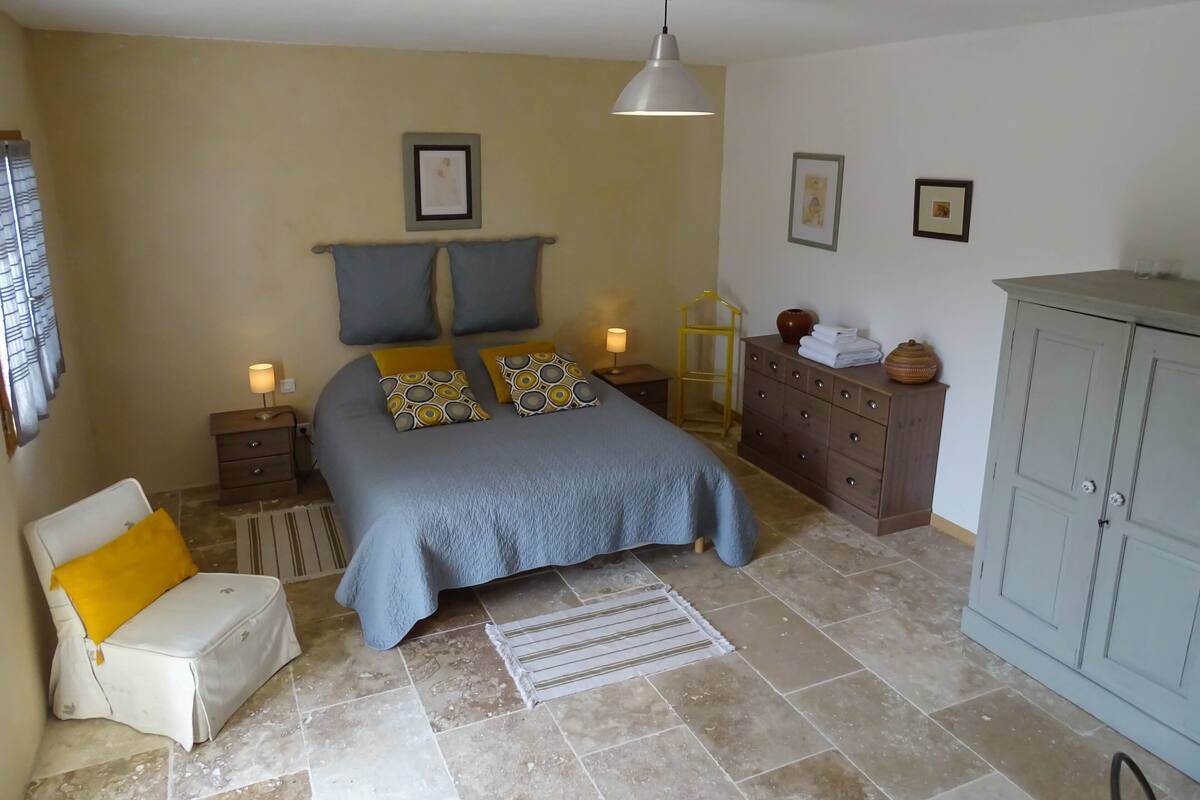 A bedroom with a bed, bedside tables, a dresser, a chair, and a cabinet.