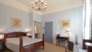 A bedroom with a wooden bed, a desk, a chair, a desk lamp, a chandelier, and two framed pictures on the wall. - Clos St Pierre de Fraisse (Avignon)